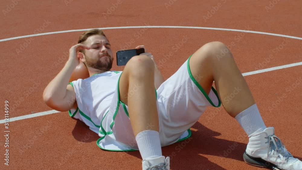 Basketball Fan Reaction Concept - Disappointed basketball player in basketball outfit watching his favorite team on smart phone, 4k slow motion Basketball Fan Reaction Concept - Disappointed basketball player in basketball outfit watching his favorite team on smart phone, 4k slow motion