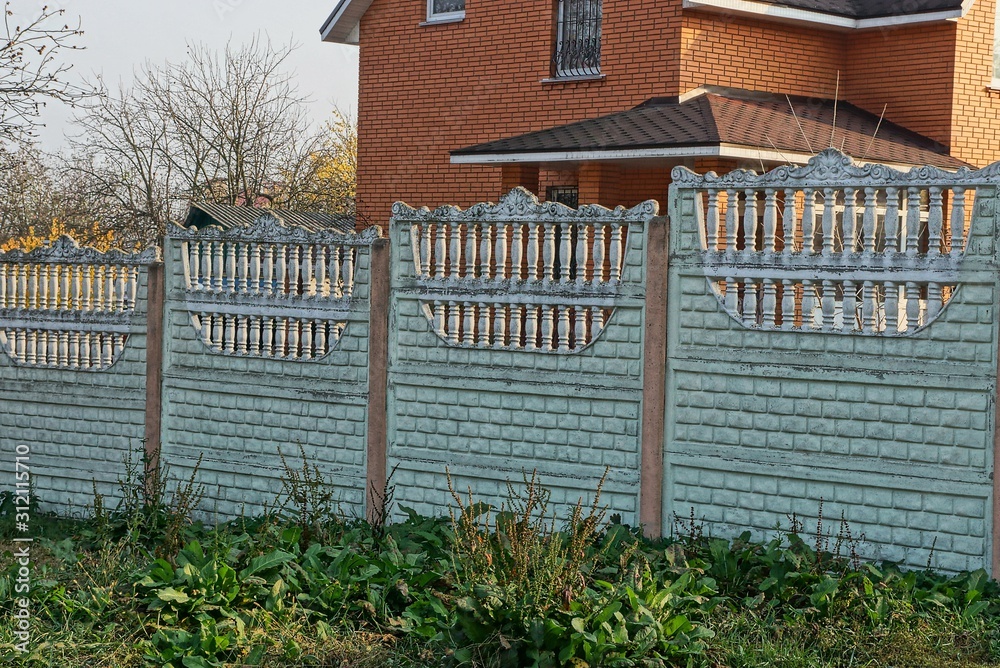 private gray concrete fence in green vegetation on a rural street