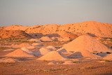 Discarded mounds of rock and sandstone mine talings outside outback town of Coober Pedy at sunset