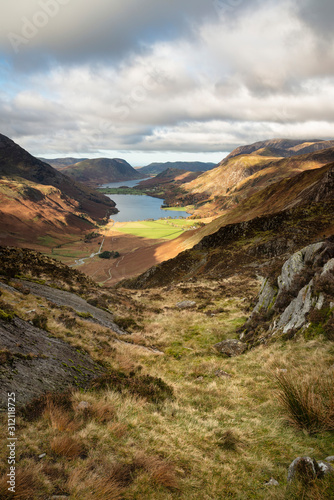 Fototapeta Naklejka Na Ścianę i Meble -  Majestic vibrant Autumn Fall landscape of Buttermere and Crummock Water flanked by mountain peaks of Haystacks High Stile and Mellbreak in Lake District