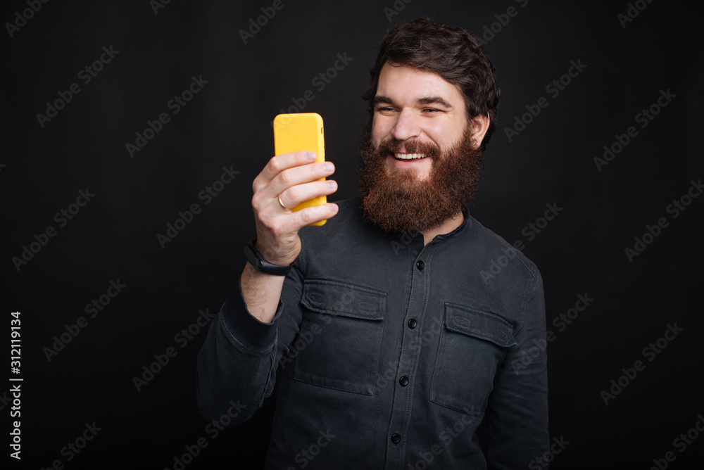 Happy man with beard using his smartphone Happy man with beard using his smartphone