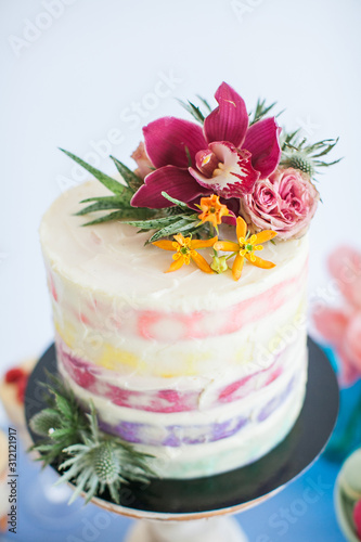 Cake decorated with rose, orchids and succulent. Great desserts surrounded by flowers. Boho style scenery for a sweet table for a celebration, celebration or wedding.