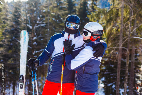 Young happy couple lying in snowy mountains with cross ski photo