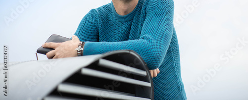 A man in a blue knitted sweater. Shoulders and arms. photo