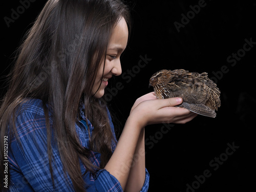 Portrait of a girl with a quail on a black background