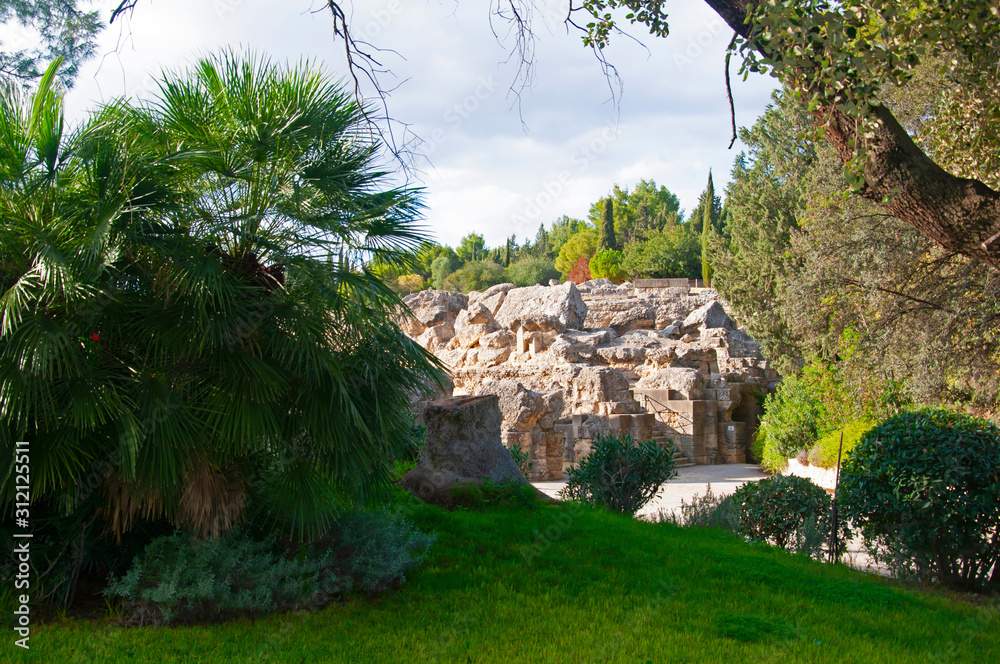 Ancient ruined roman walls and green trees in the national park in Seville, Spain