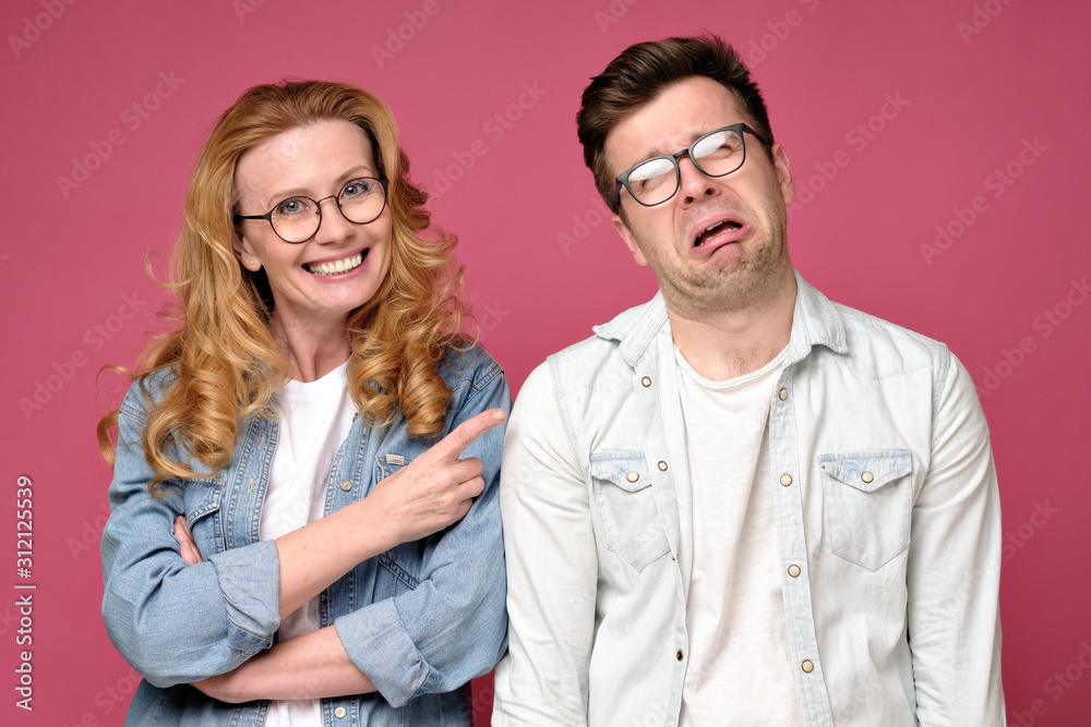 Caucasian mature man laughing on problems of her coworker man. Studio shot of red wall background. Caucasian mature man laughing on problems of her coworker man. Studio shot of red wall background.