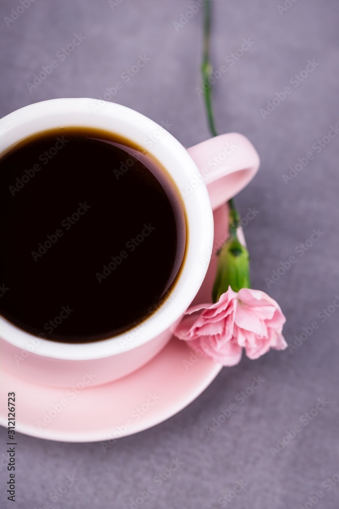 Pink cup of black coffee and pink carnation flower on a gray concrete background Pink cup of black coffee and pink carnation flower on a gray concrete background