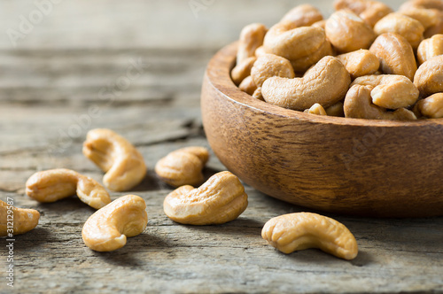 roasted salted raw cashew nuts in wooden bowl on rustic table, healthy vegetarian snack, Anacardium occidentale photo