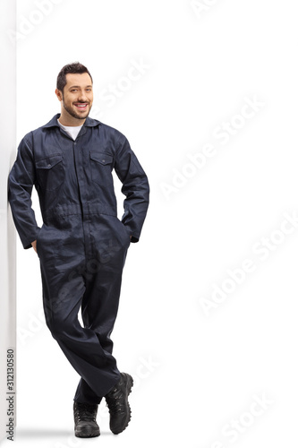 Fotografie Male worker in an overall uniform leaning on wall