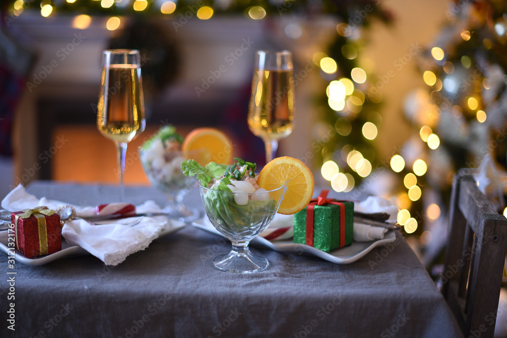 decorated New Year's table or Christmas table  . Closeup of two glasses of champagne in front of burning fireplace