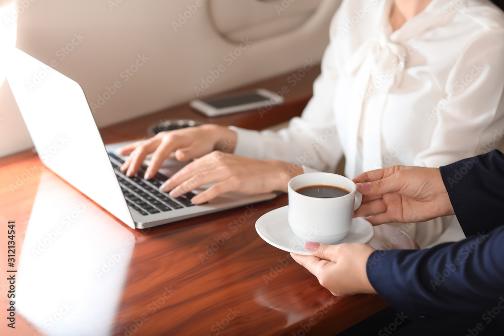 Air hostess bringing coffee for businesswoman on board the modern private airplane Air hostess bringing coffee for businesswoman on board the modern private airplane