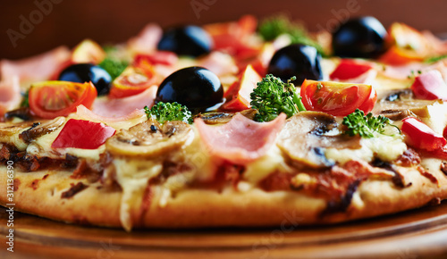 Healthy pizza with ham, broccoli, cherry tomatoes, red pepper and champignon mushrooms. Close up.