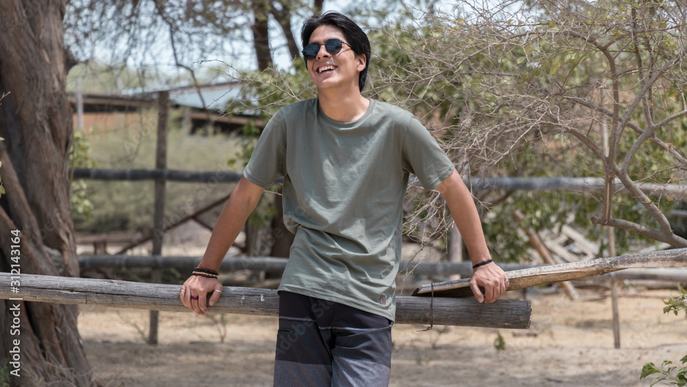 young man standing in the middle of the forest while smiling with sunglasses on young man standing in the middle of the forest while smiling with sunglasses on