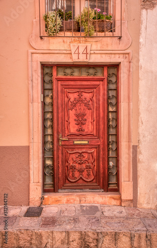 A beautifully carved vintage door with a metal, glass and stone frame and a salmon wall © mauro53