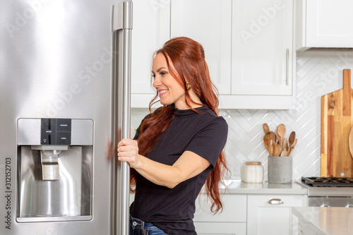 A woman looks inside a refrigerator in a beautiful modern farmhouse kitchen photo