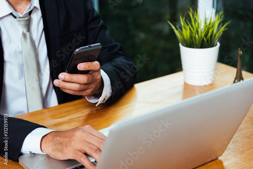 Business man working on mobile smart phone with laptop computer