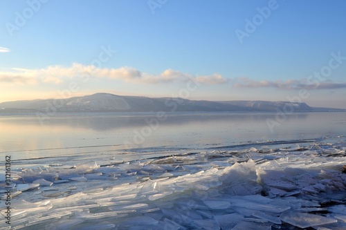 Winter landscape with a smooth surface of the river covered with ice