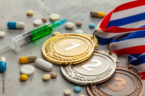 Doping for athletes. Golds, silver and bronze medal and doping syringe and pills with capsules on a gray background photo