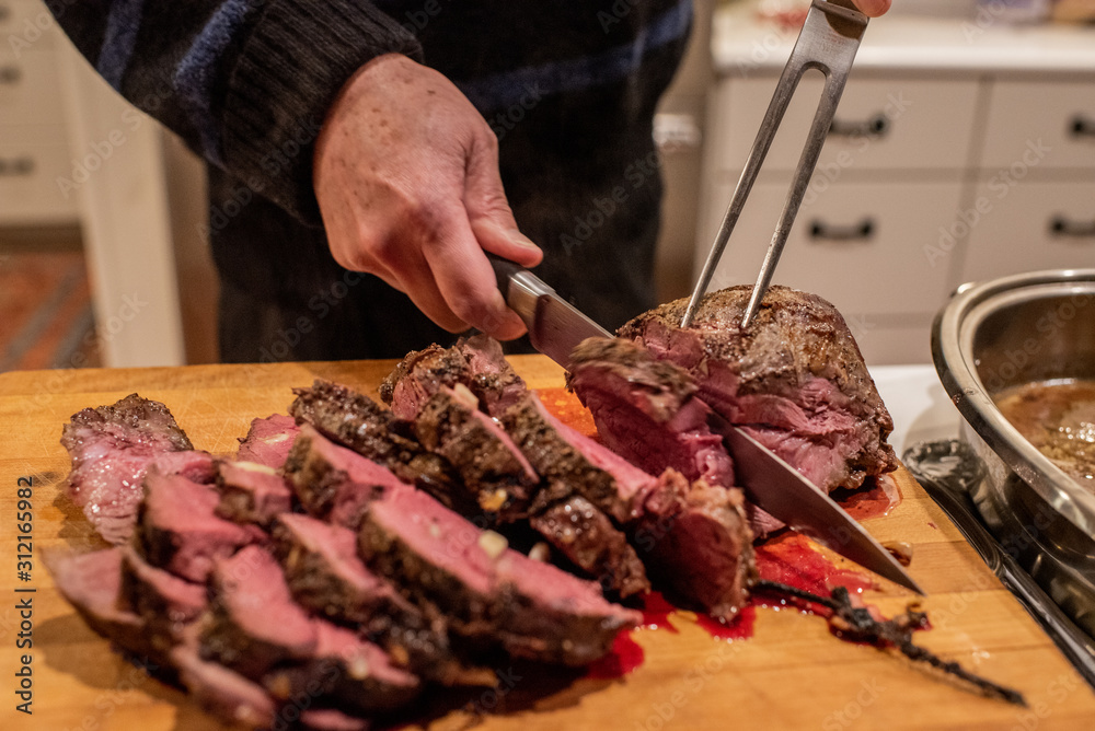 A chef cuts freshly cooked red meat