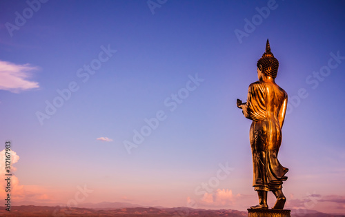 Big standing Buddha statue and the sky at sunset.