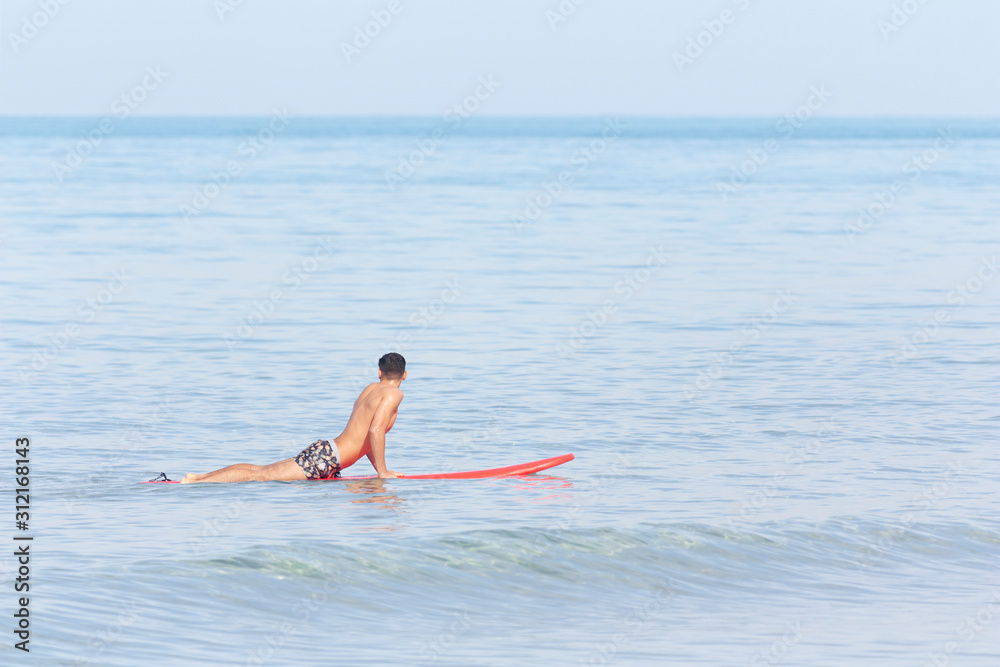 Handsome guy lying on surfboard on water