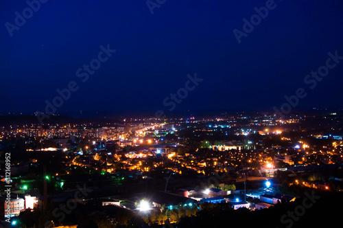 Night cityscape of many buildings and lights. Classic blue dark sky at evening