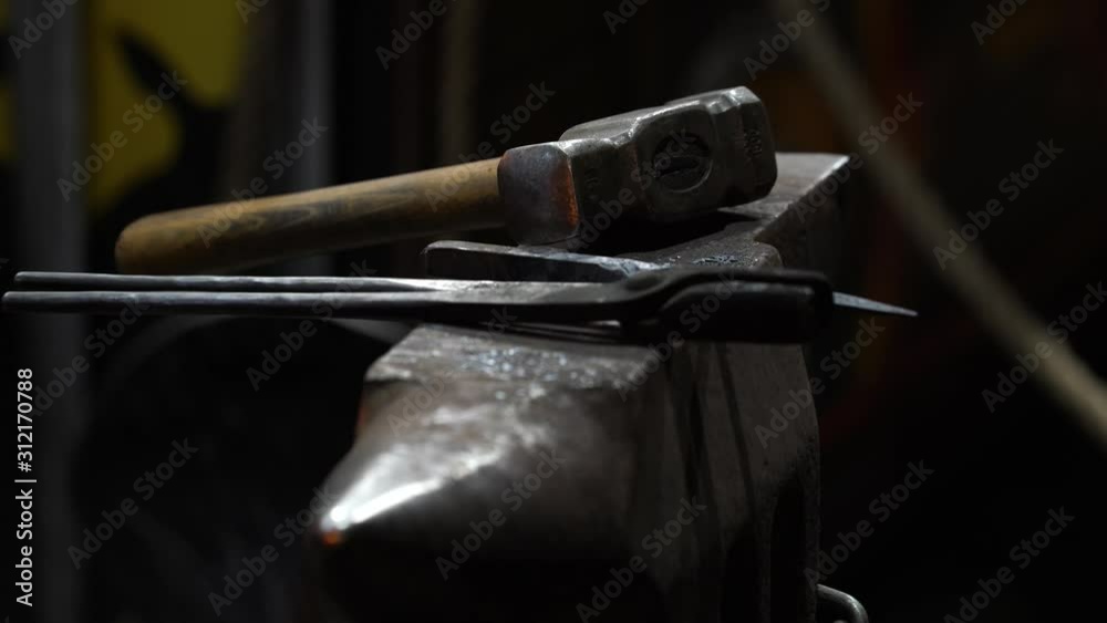 Blacksmith anvil with a hammer and a pair of pliers seen through a fire Blacksmith anvil with a hammer and a pair of pliers seen through a fire
