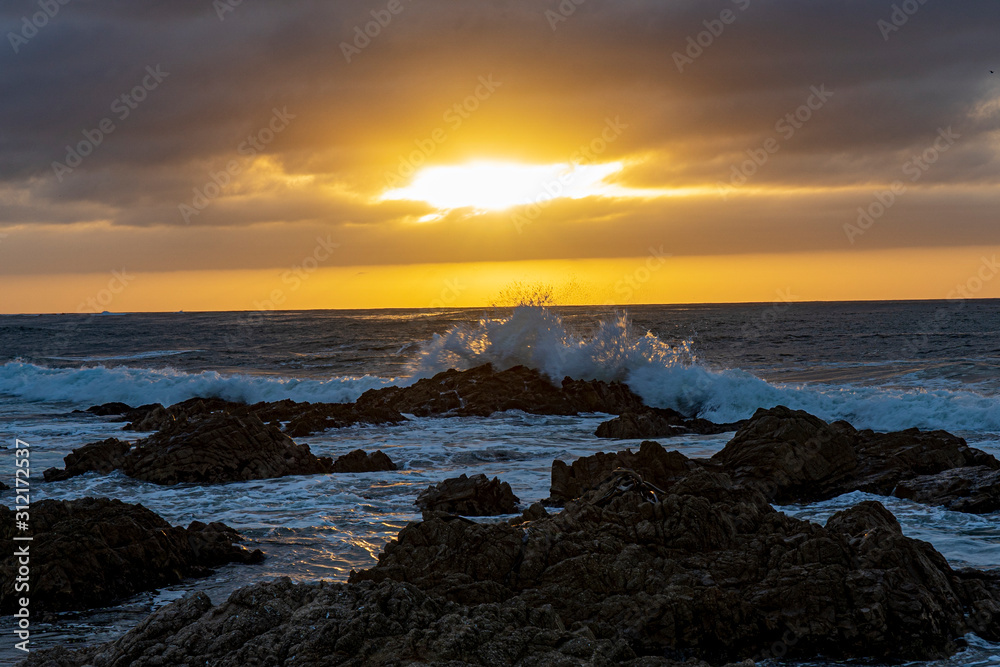 A brilliant sunset illuminates the rough surf