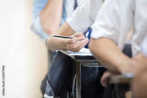 high school university student study.hands holding pencil writing paper answer sheet.sitting lecture chair taking final exam attending in examination classroom.concept scholarship for education abroad