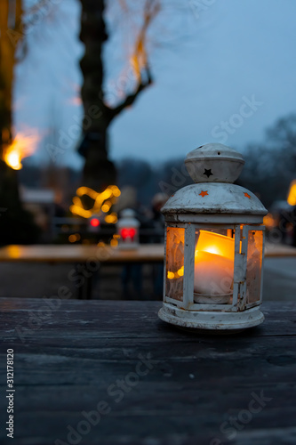 a white lantern with candle on a wooden table 