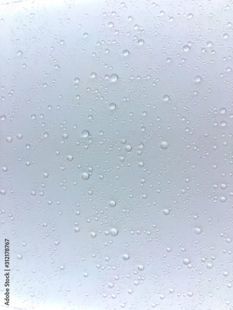 Round beautiful drops of water of different sizes on a white surface. Abstract background for design.