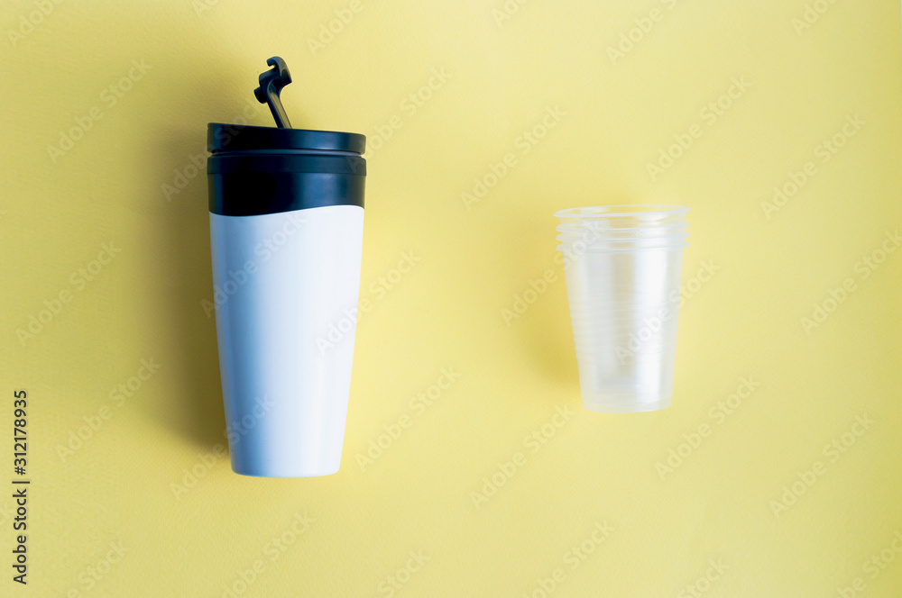 Reusable black and white takeaway coffee cup with disposable plastic cups isolated on yellow background, flat lay Reusable black and white takeaway coffee cup with disposable plastic cups isolated on yellow background, flat lay