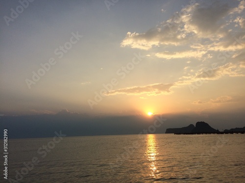 The morning sun shines through the clouds reflecting the sea and mountains  giving a fresh and relaxing feeling.