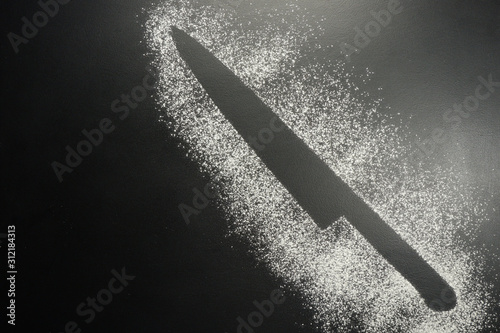 Drawing flour on a black board. Kitchen knife