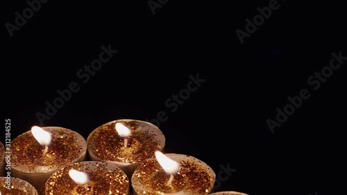 Background of tealight cup glitter Candles Lights shines yellow gold bright for celebration, religion, anniversary Festival.  Candle spins rotates around and flame move by wind, copy space black bmpcc photo