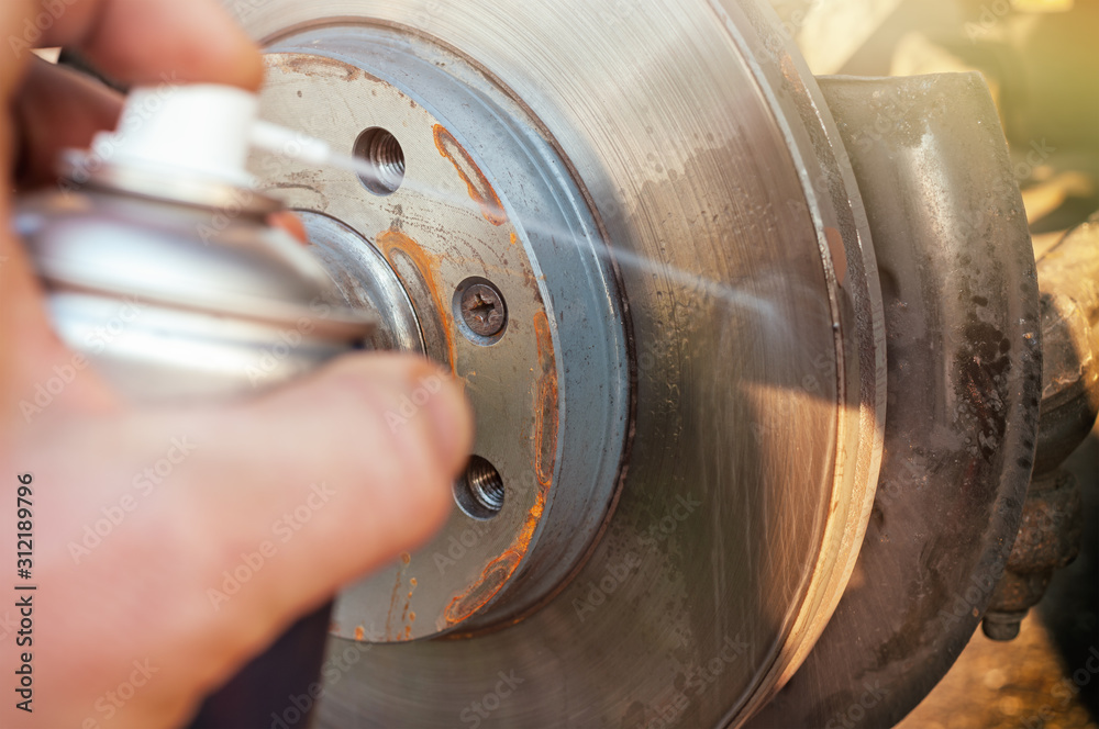 Car disk brake cleaning with spray.