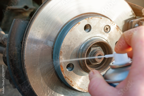 Car disk brake cleaning with spray.