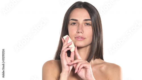 Close-up of a beautiful young woman gently touching skin of her face with white soap. Skincare concept