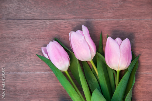Fototapeta Naklejka Na Ścianę i Meble -  Soft baby pink tulips (Tulipa Gesneriana) lying on wooden table - flatlay view.