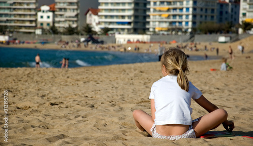 Young girl sitting on the beach in spring.