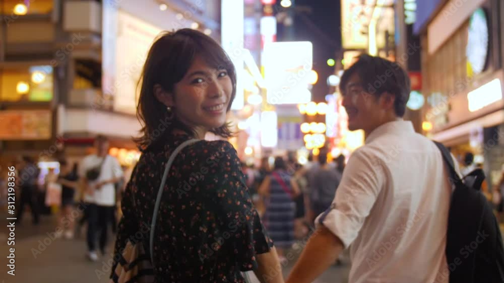 Beautiful women looking back at camera slow motion walking holding hands with boyfriend trip