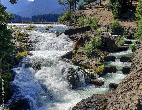 Cascading Clear Lake Falls with Fish Ladder surrounded by rocky cliffs with clouds and a blue sky in summer east of Mount Rainier near Rimrock Lake Washington State photo