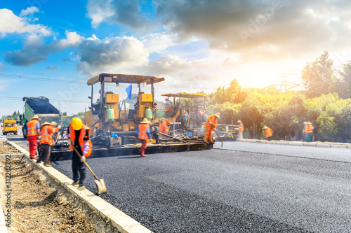 Construction site is laying new asphalt road pavement,road construction workers and road construction machinery scene.