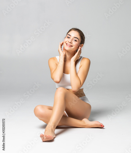 Wellness and beauty concept. Beautiful slim woman in white underwear sitting on white floor