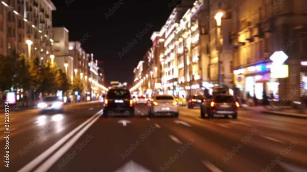 POV, Driving a car. Hyperlapse 4K. Defocused view from the car through the windshield. Facades of buildings are beautifully illuminated. Large stream of cars. Nighttime. Night life in Moscow. Ultra HD
