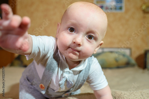 A small child plays on the bed at the parents. Happy childhood.