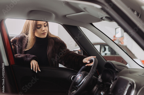 A young businesswoman is testing cars in a car store © dsheremeta