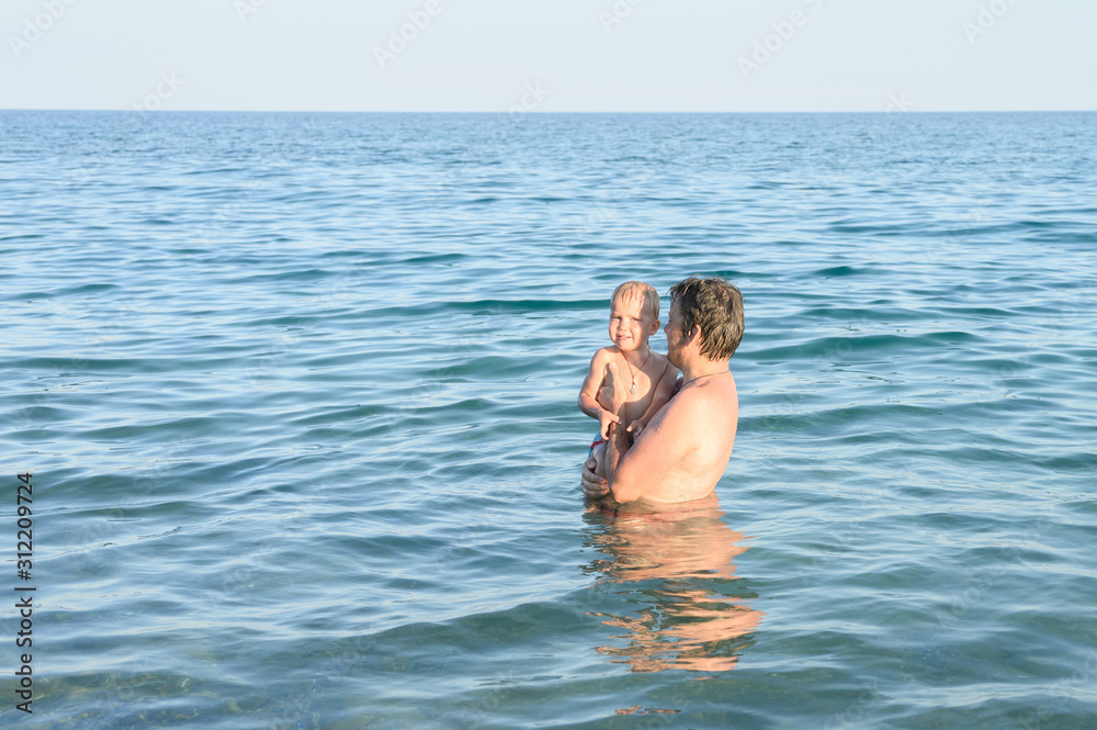 three year old little boy having fun at summer vacation in sea with his family