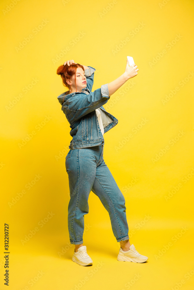 It's easier to be follower. Need minimum clothes for selfie. Caucasian woman's portrait on yellow background. Beautiful female red hair model. Concept of human emotions, facial expression, sales, ad. It's easier to be follower. Need minimum clothes for selfie. Caucasian woman's portrait on yellow background. Beautiful female red hair model. Concept of human emotions, facial expression, sales, ad.